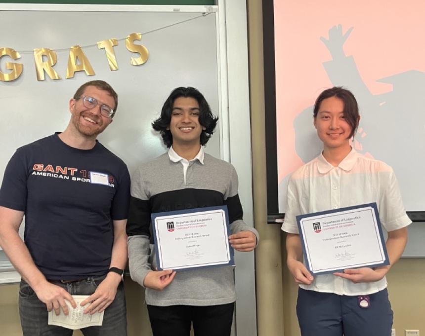 Dr. Dustin Chacón stands with Linguistics undergraduate students Zahin Hoque and Jill McLendon, both of whom are holding certificates. 