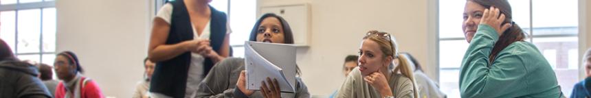 Students in a classroom looking at a notebook and working together.