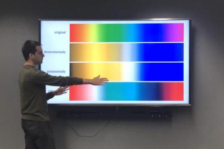 Joey Stanley standing in front of digital images of color examples